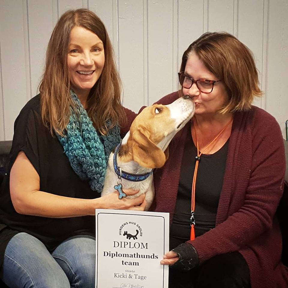 Hundpsykolog Kicki Fellstenius och diplomathunden Oskar tar emot diplom från Cilla Danielsson på Hundens Hus.